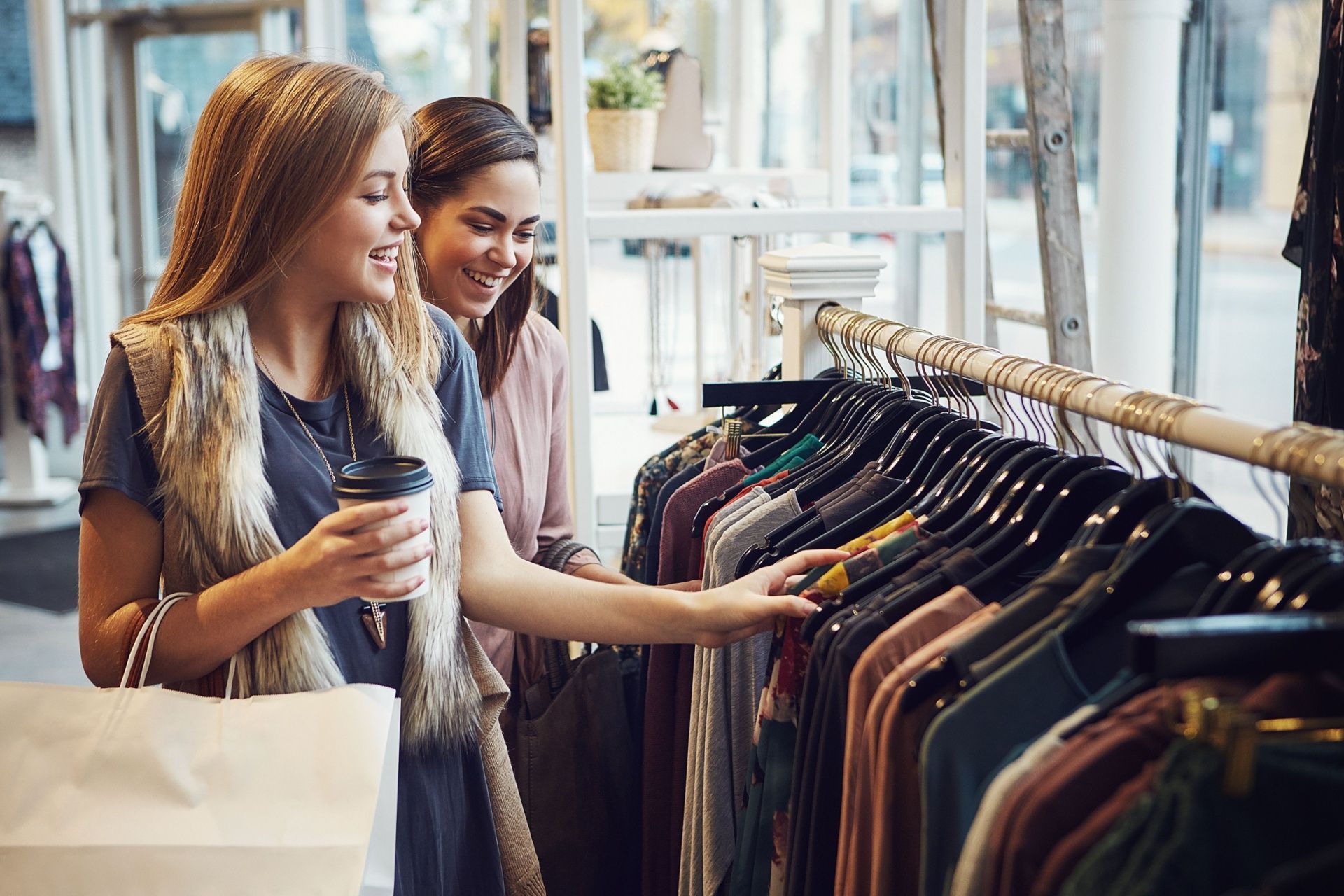 Two shoppers browsing clothes on a rack in a bright boutique