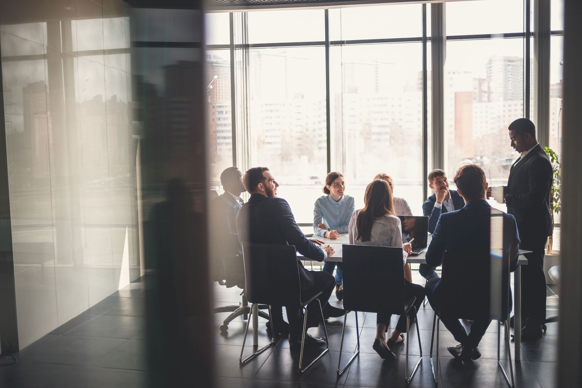 People in a bright conference room seated around a table during a meeting