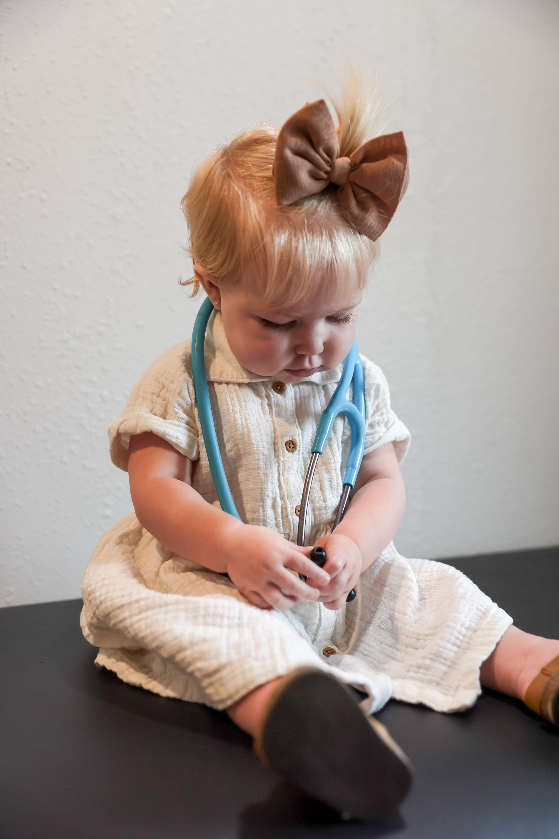 Little girl sitting on a pediatrician's exam table with a stethoscope