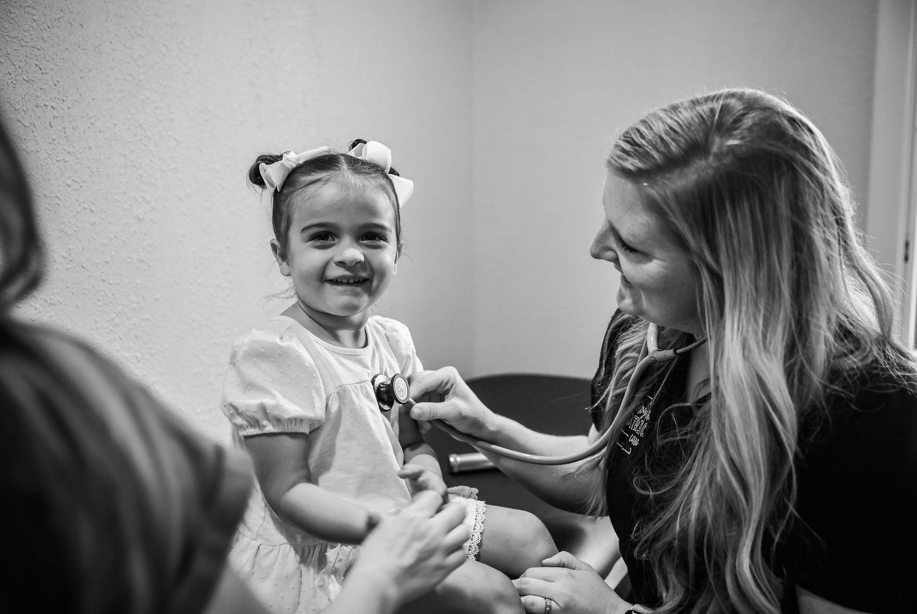Pediatrician listening to the heart beat of a smiling little girl