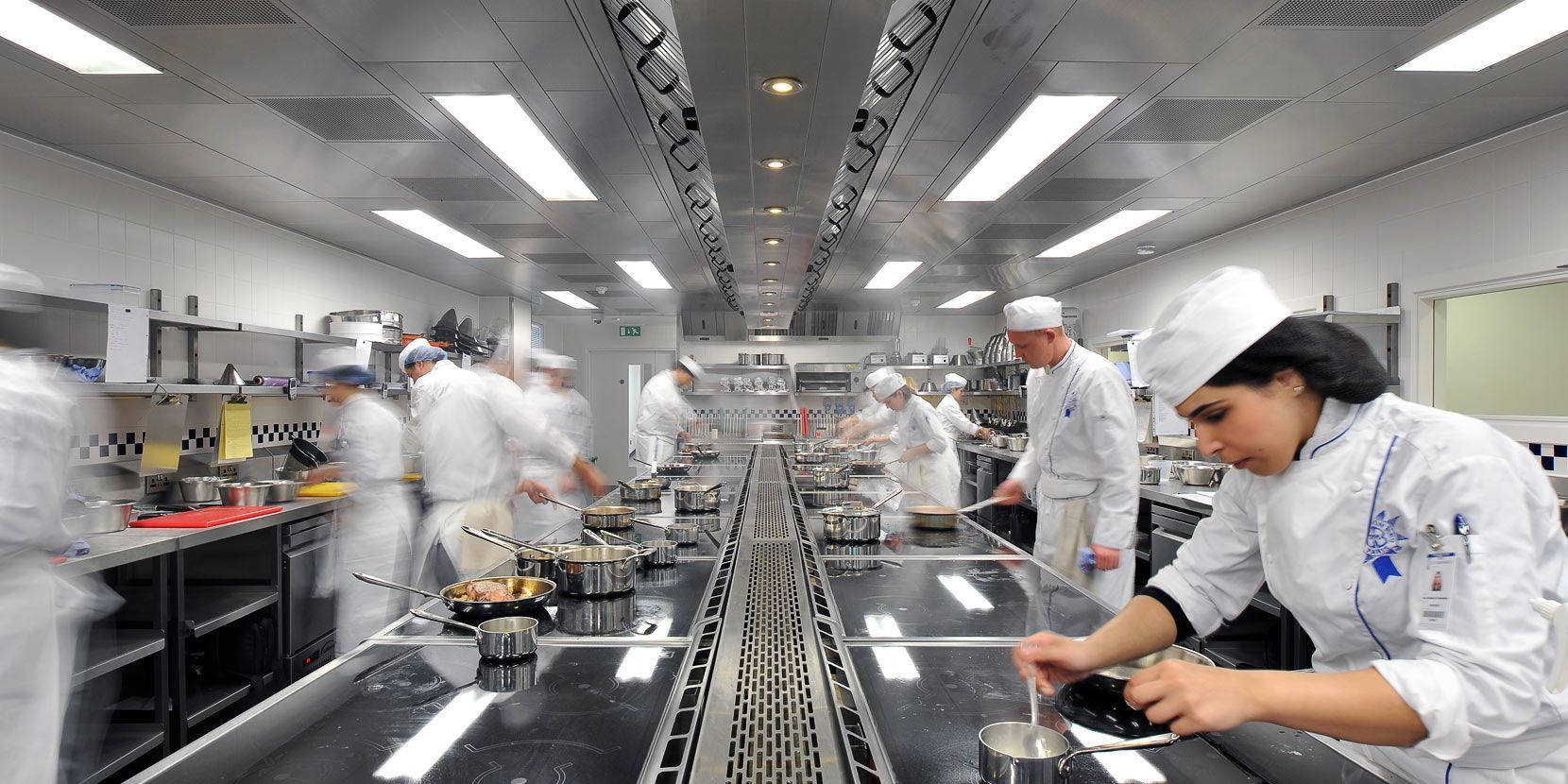 A group of chefs are preparing food in a large kitchen.