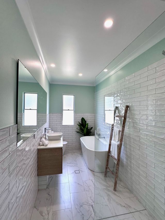 A bathroom with two sinks , a tub and a mirror.