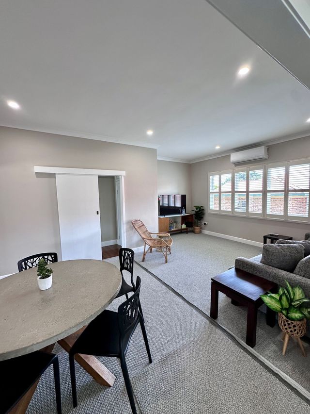 A living room with a couch , table , chairs and a television.