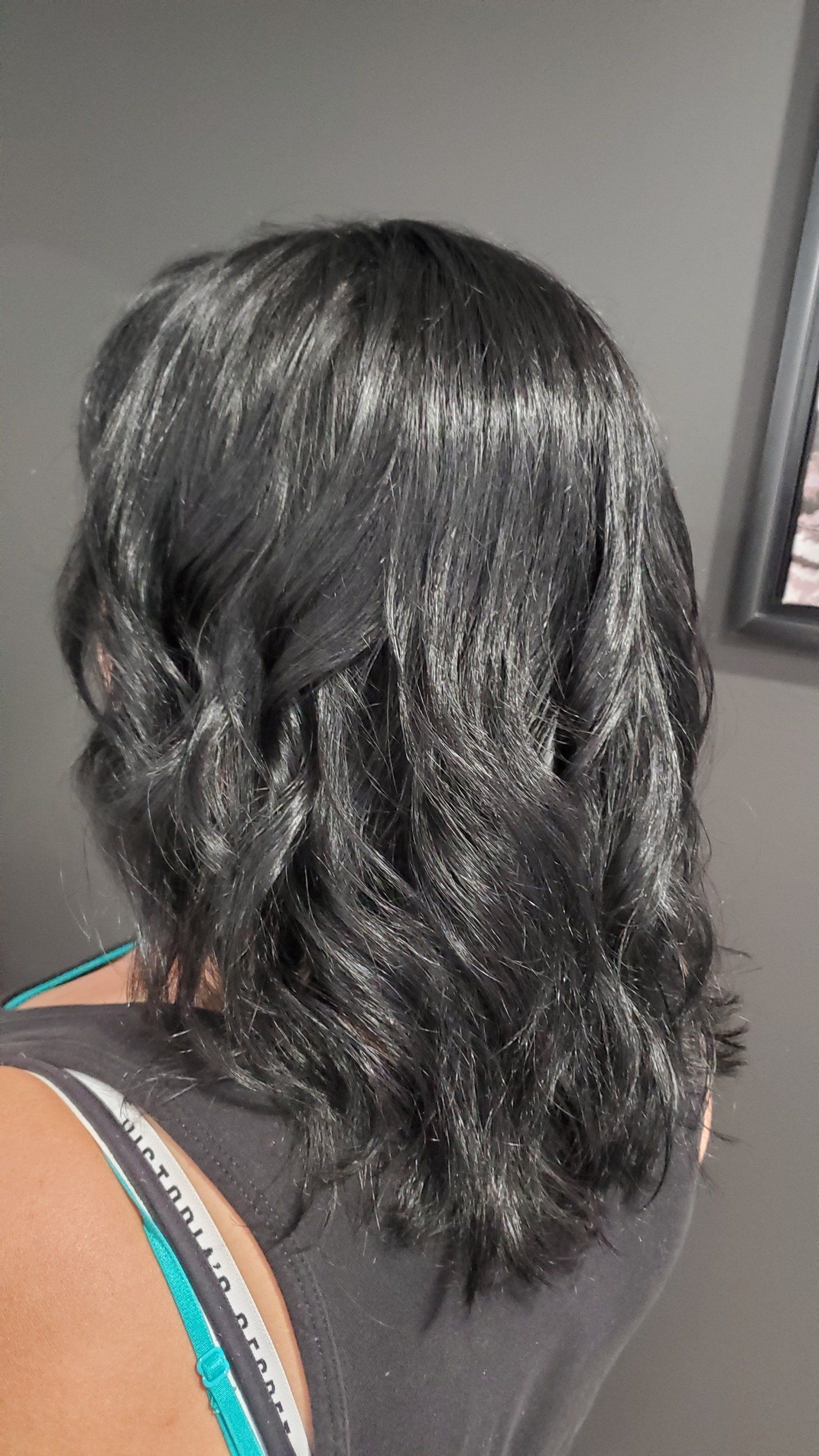 Black hair with loose waves. Sparkling appearance. Person from the back, wearing a black top.