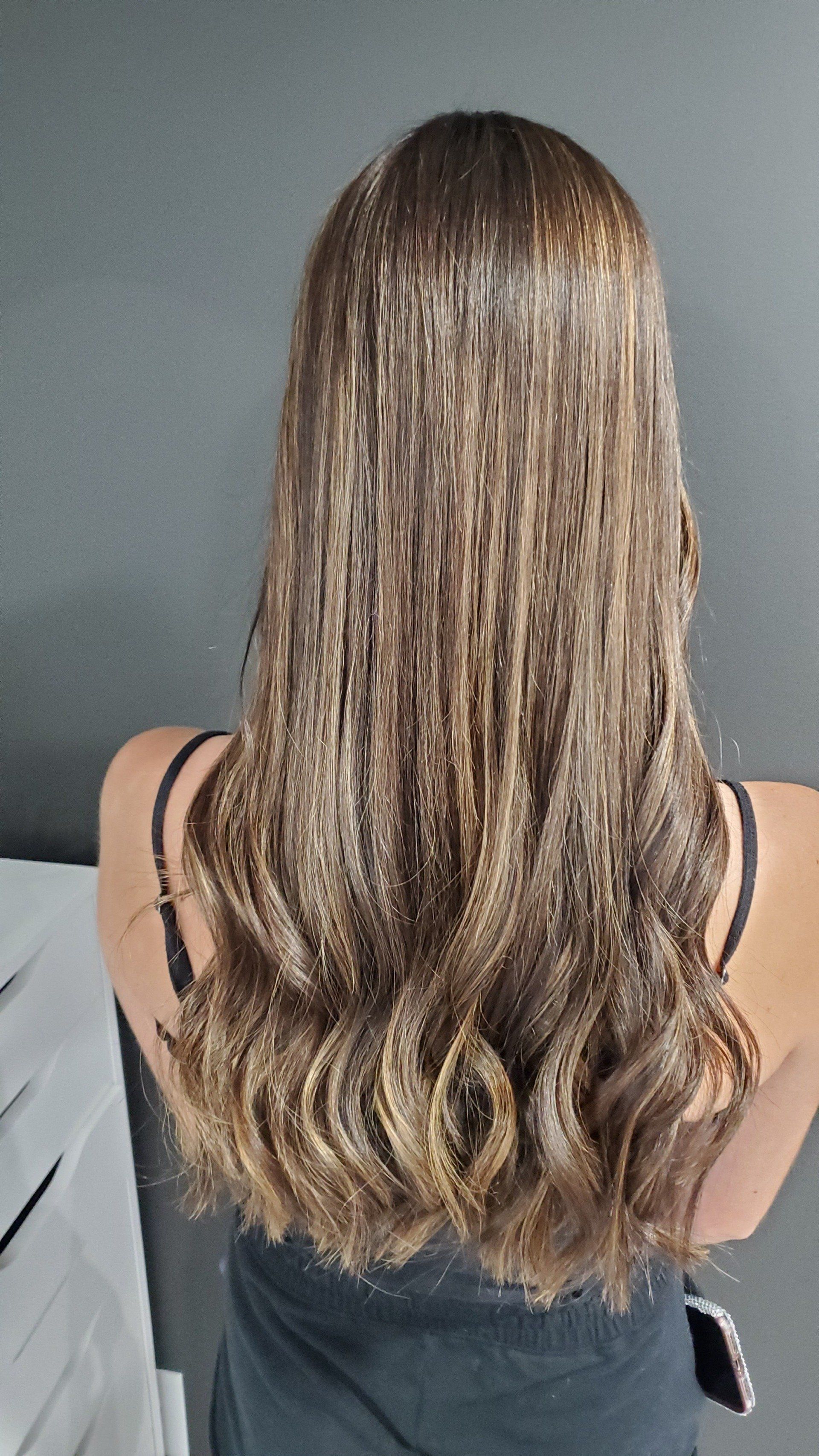 Long wavy brown hair with glitter, person's back to the camera, wearing a black tank top.