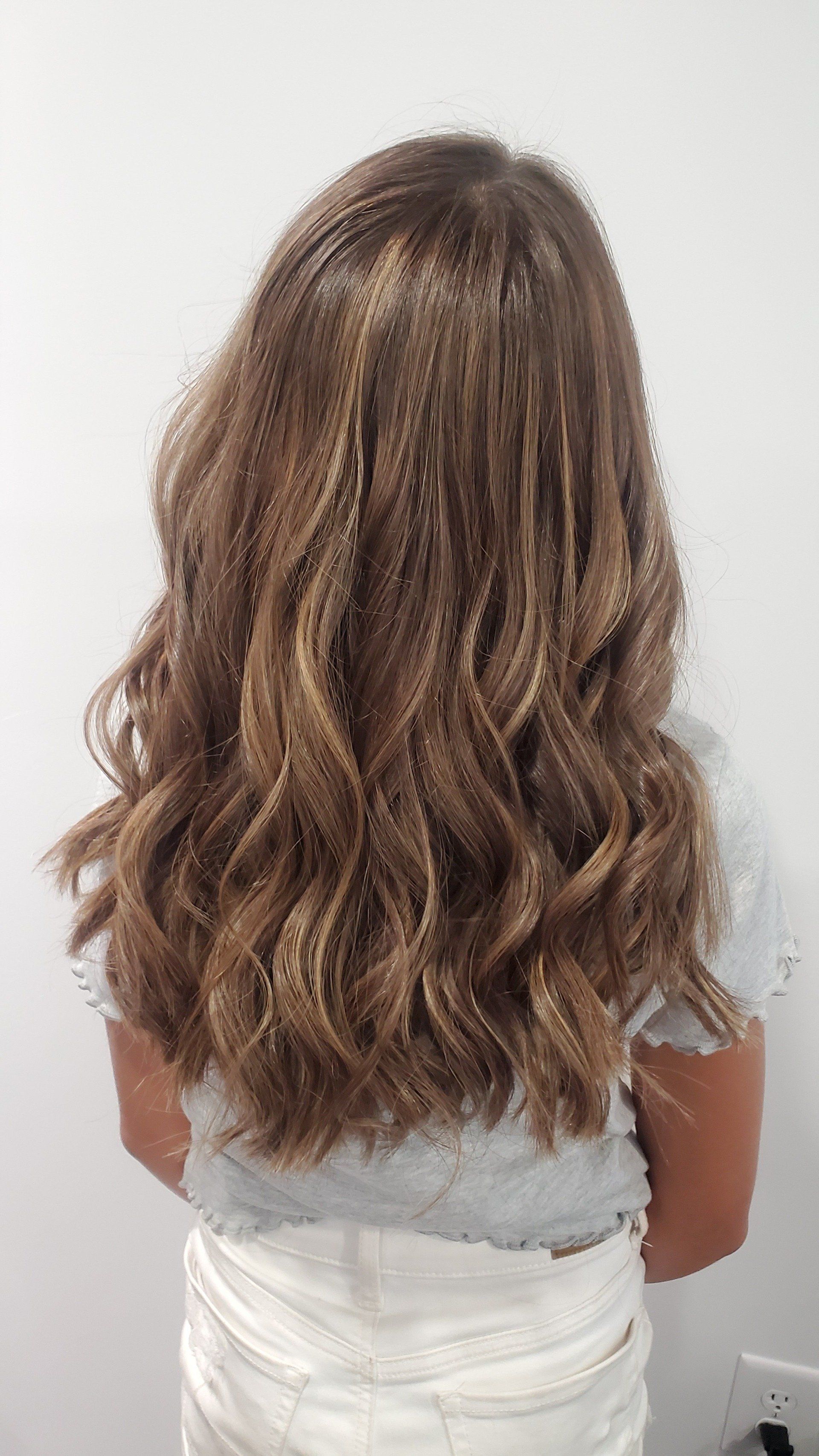 Woman with long, wavy brown hair with blonde highlights.