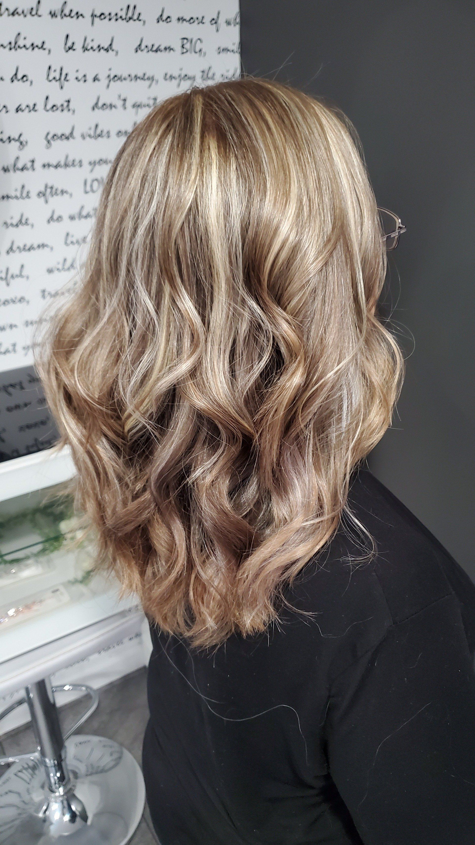 Woman with wavy, highlighted hair; salon setting.