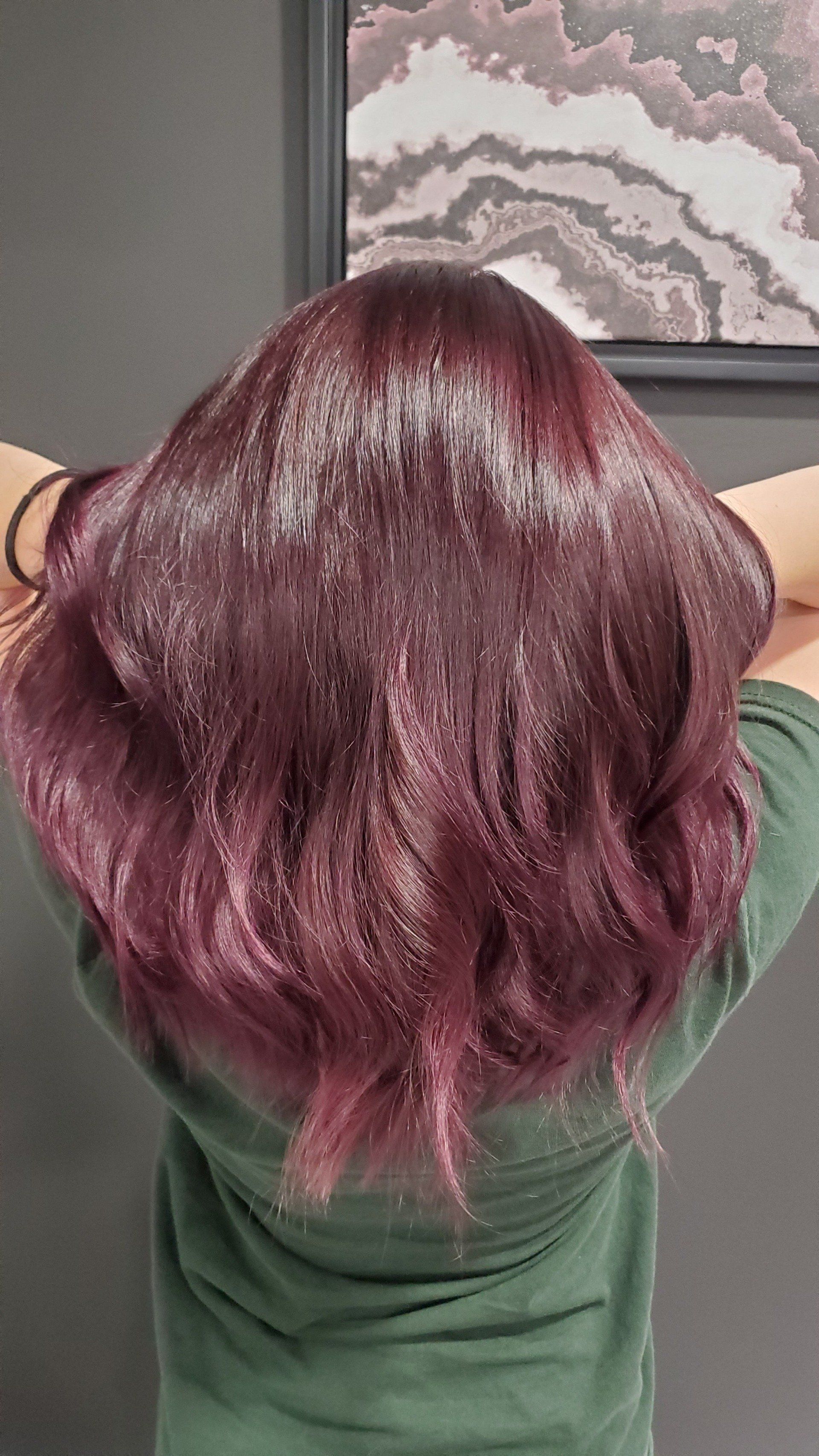 Person with long, wavy, deep-purple hair sprinkled with glitter. Hands are behind the head.