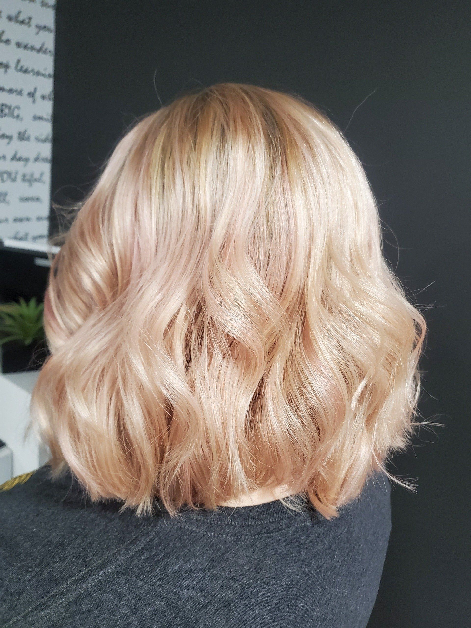 Blonde hair styled in loose waves, angled bob, possibly with a pink tint.