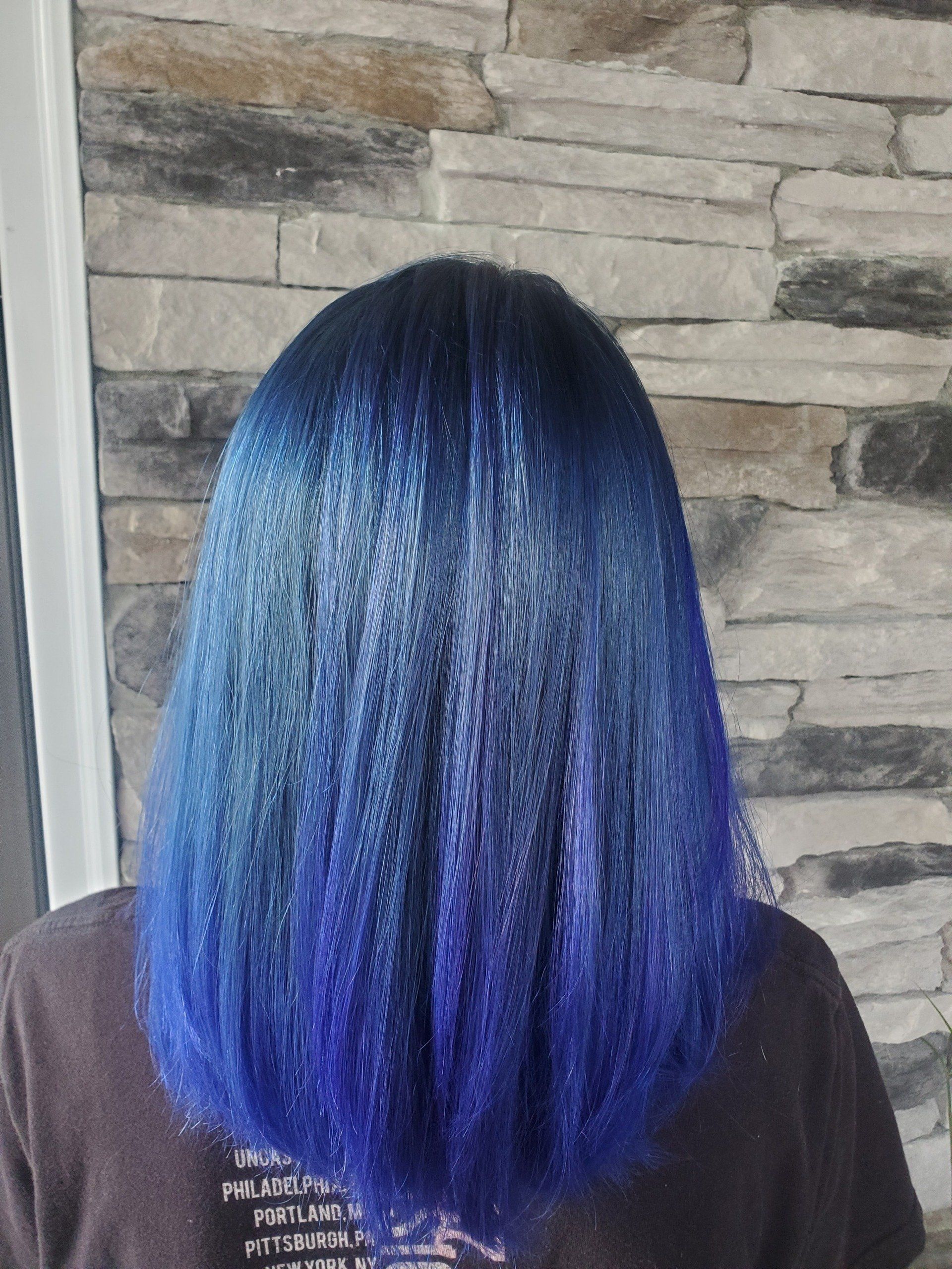 Woman with blue ombre hair, dark at the roots, fading to vibrant blue.