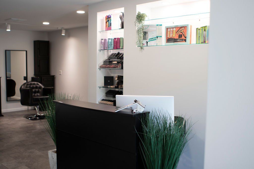 Salon interior with reception desk, shelves with products, and a mirror.