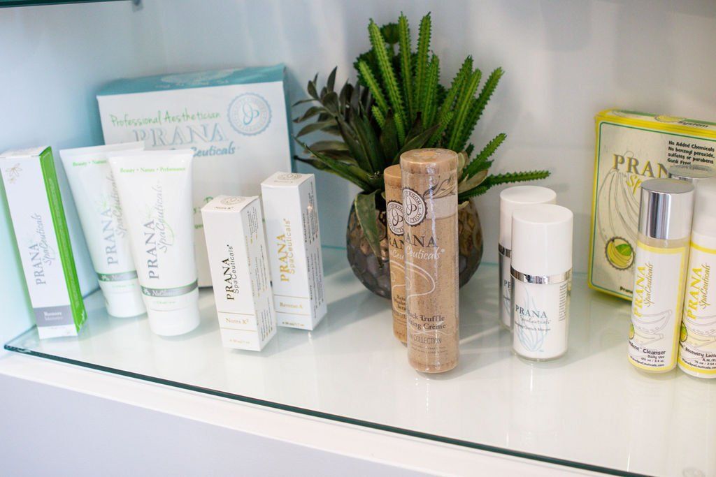 Cosmetics display on a shelf, featuring skincare products and a small plant arrangement.