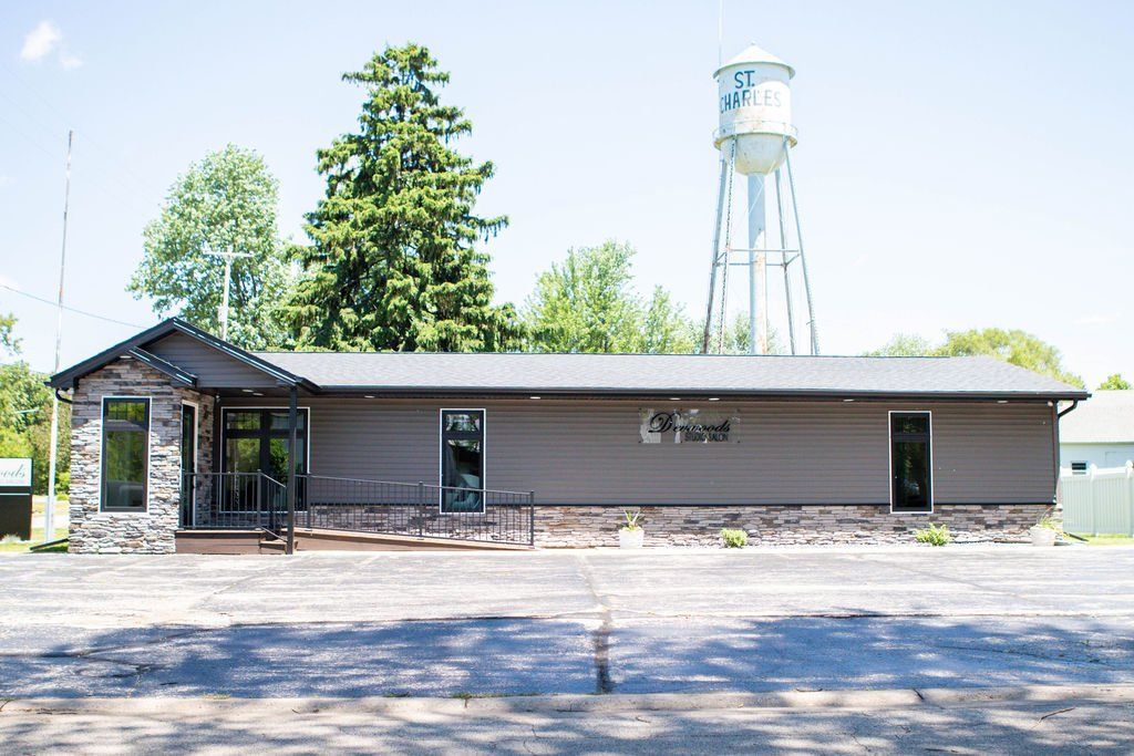 Brown building with a water tower in the background and a paved parking area.