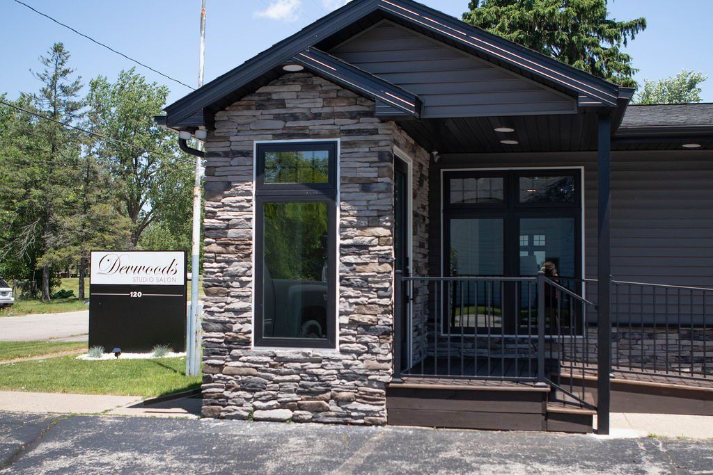 Exterior of a commercial building with stone and dark siding. Sign says 