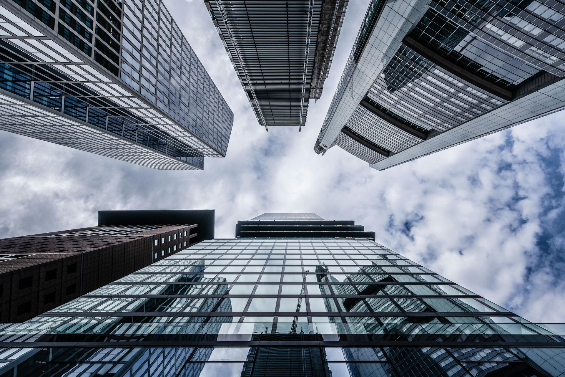 Looking up at a group of tall buildings against a cloudy sky.