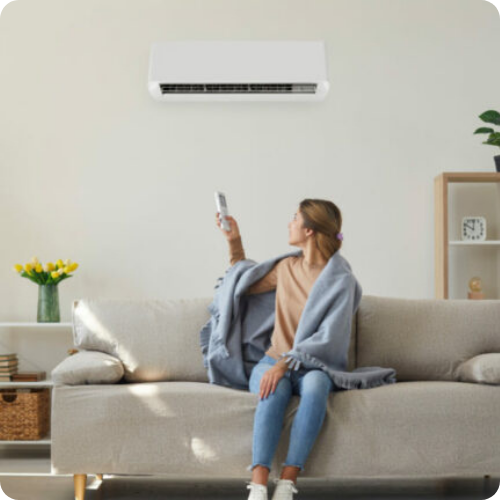 A woman is sitting on a couch holding a remote control.