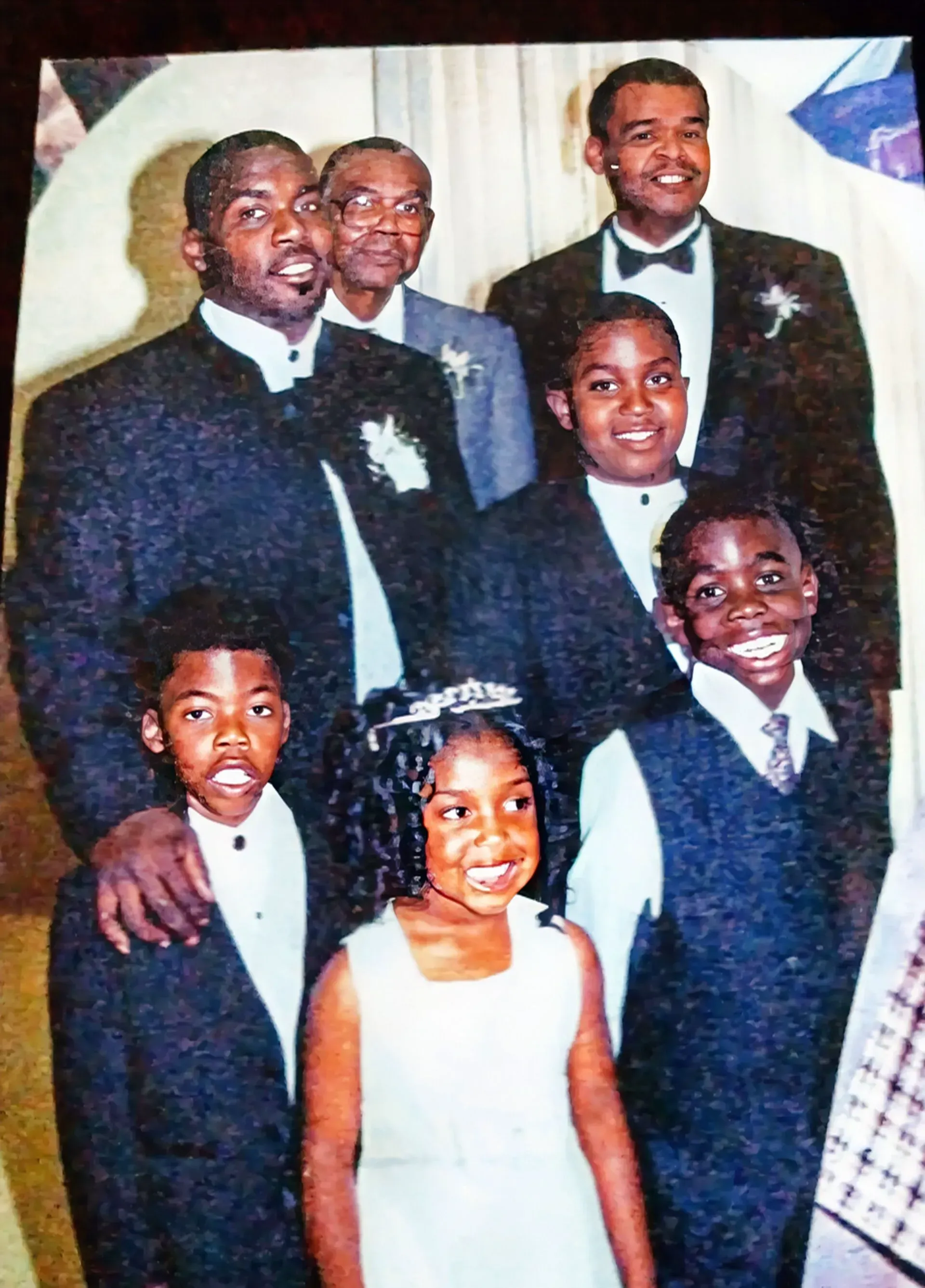 Group of people in formal attire pose for a photo; adults and children.
