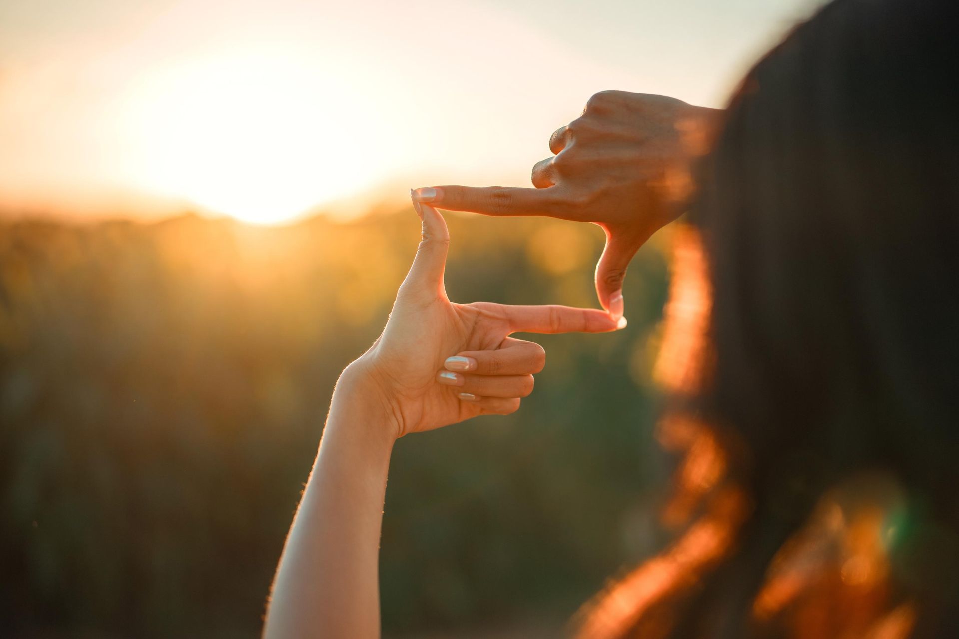Hands framing a sunset. Focus concept.