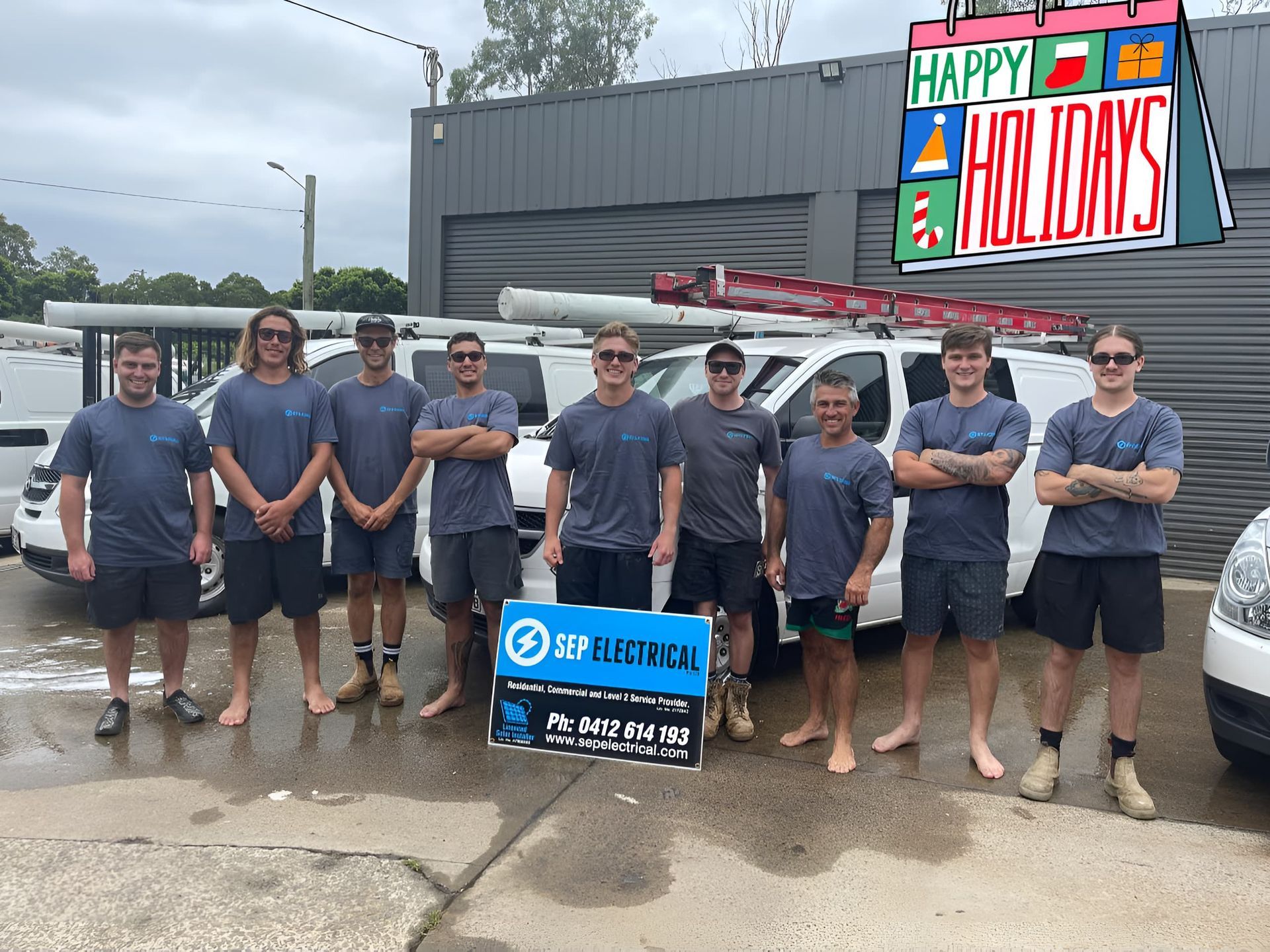 A Group of Men Are Standing in Front of a Building That Says Happy Holidays — SEP Electrical Pty Ltd in Towradgi, NSW
