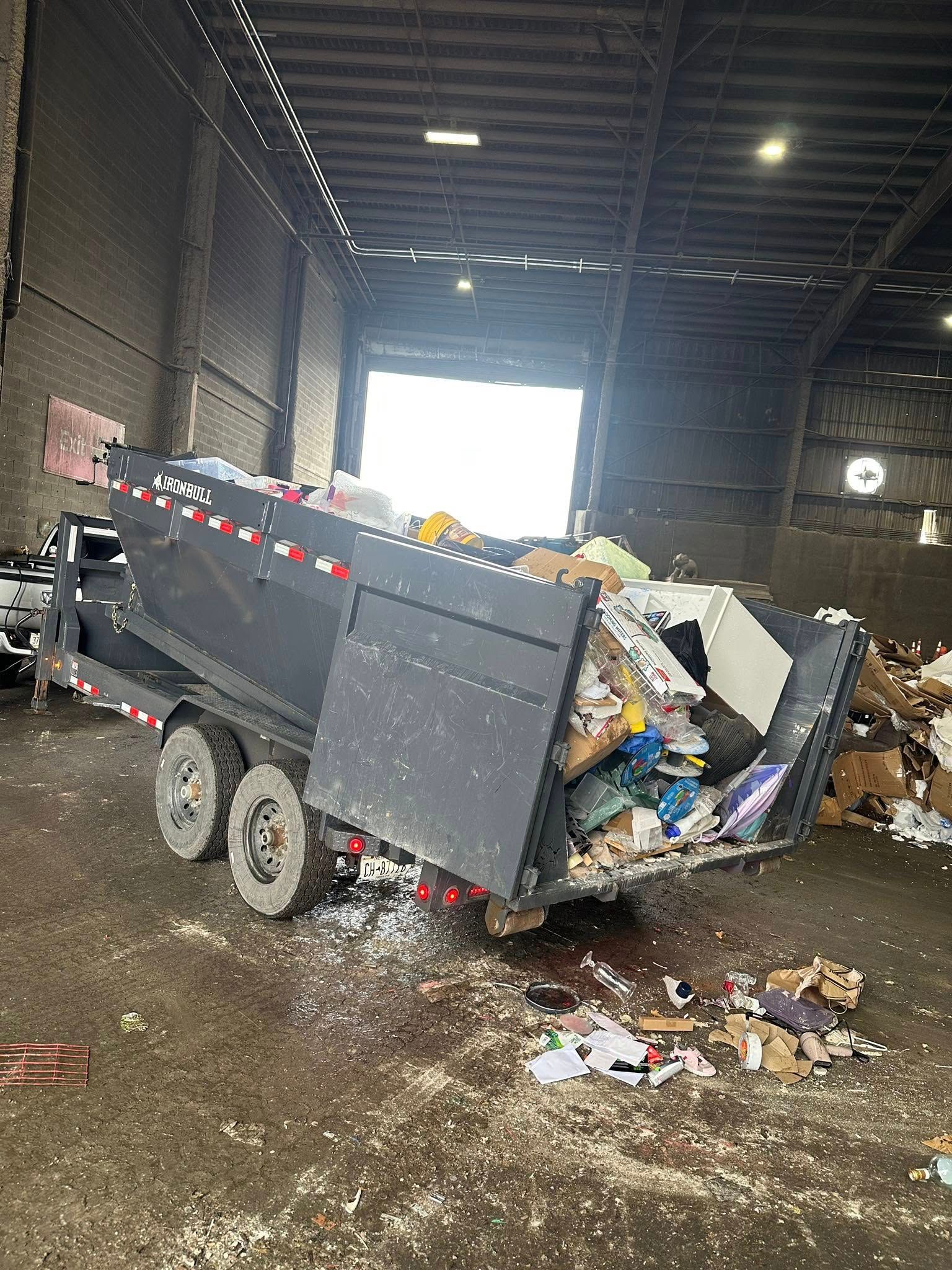 A dumpster is filled with trash in a warehouse.