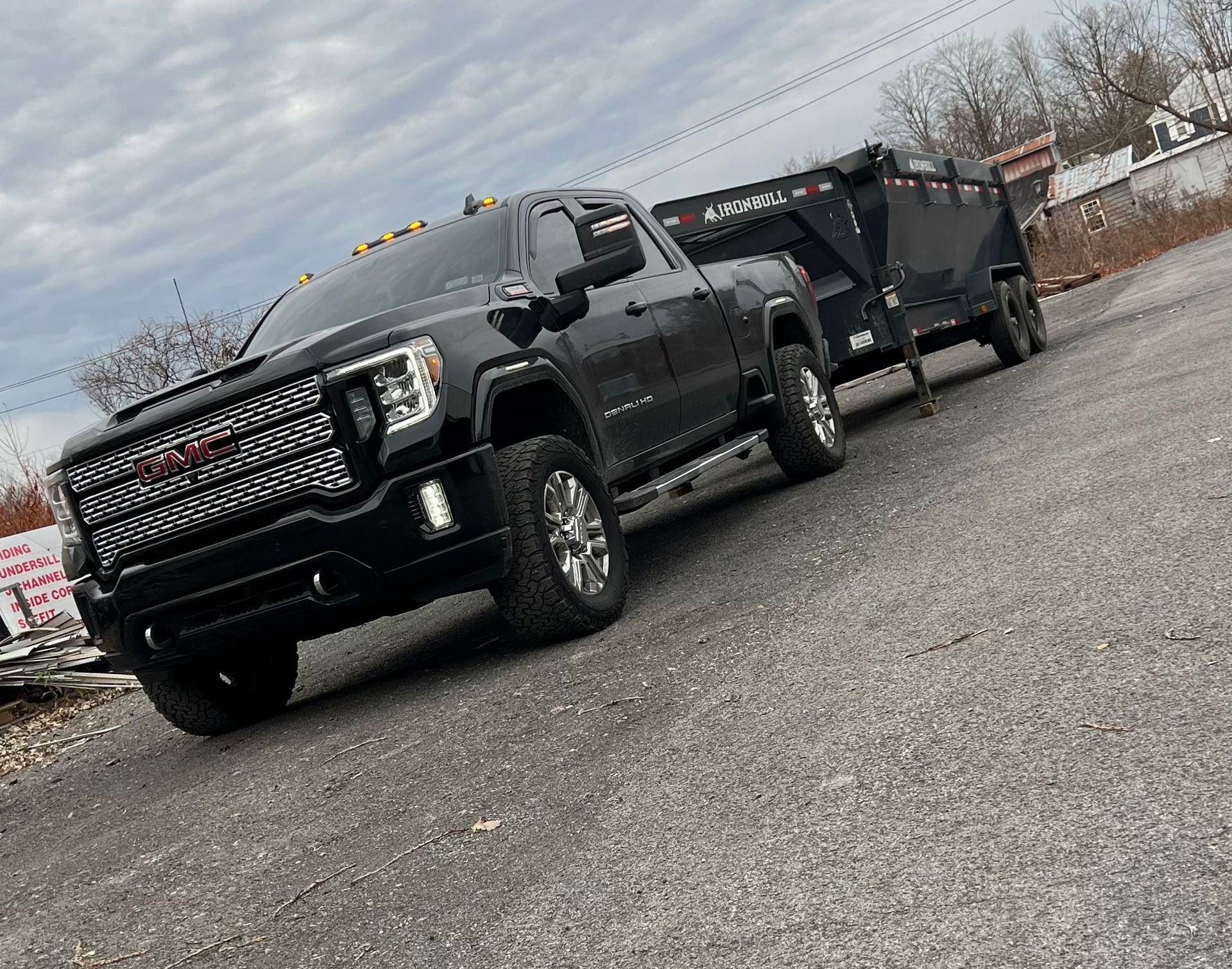 A black truck with a trailer attached to it is parked on the side of the road.