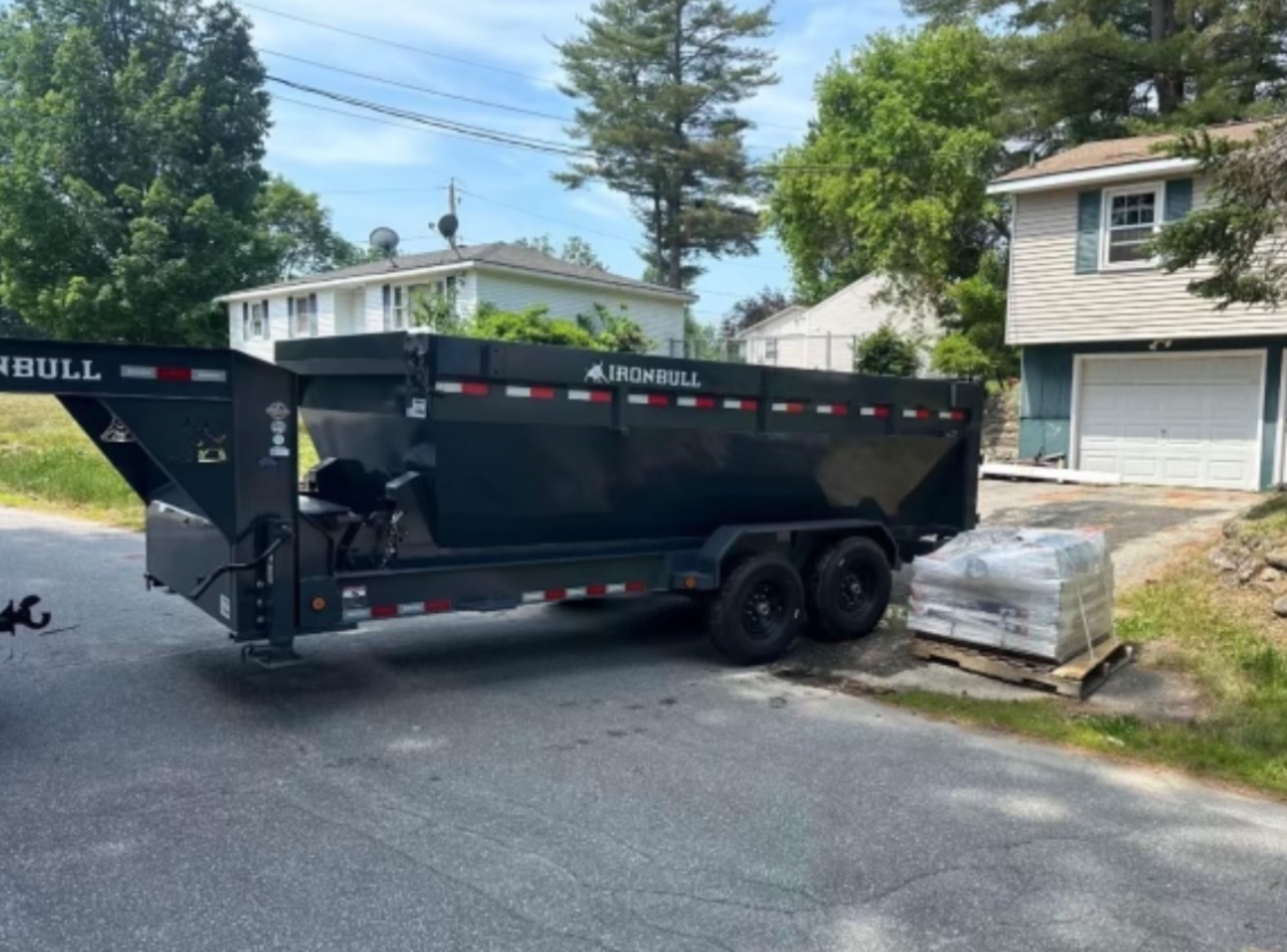 A dump truck is parked in a parking lot next to a trailer.