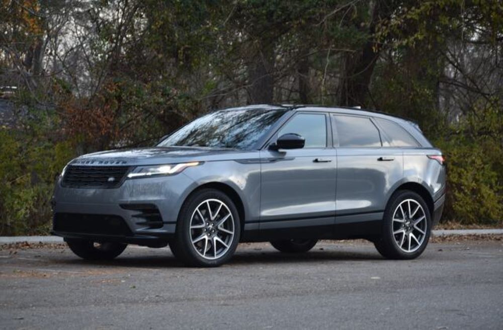 Gray Land Rover Velar SUV parked on a road with trees in the background.