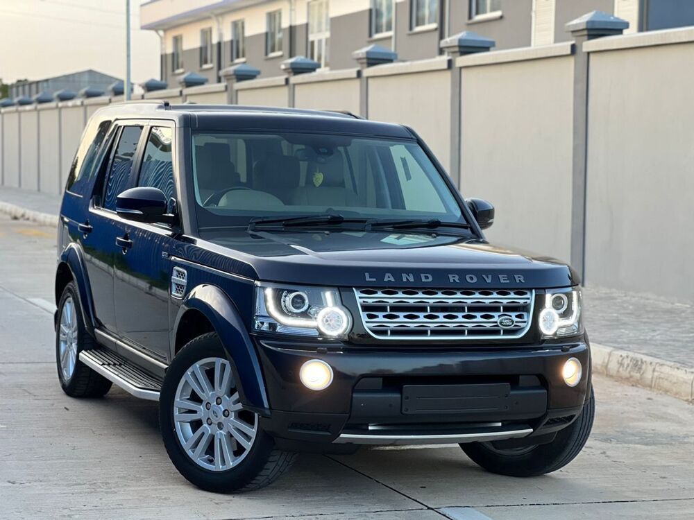 Dark blue Land Rover Discovery SUV parked outdoors in front of a gray fence.