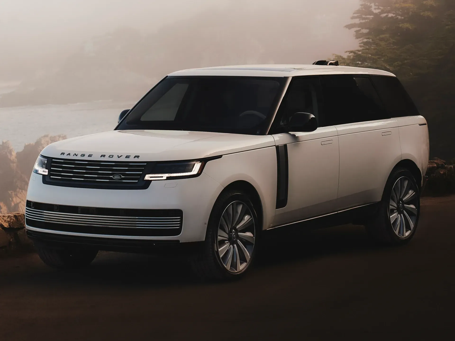 White Range Rover SUV parked on a road with a blurred, natural landscape in the background.
