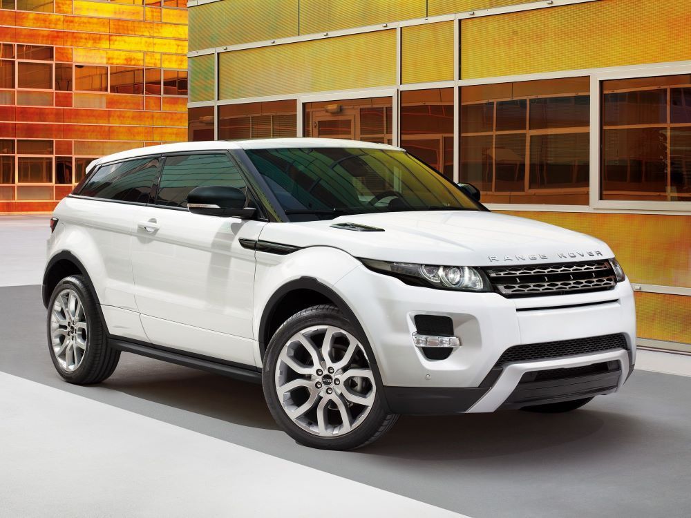 White Range Rover SUV parked in front of a building with orange and yellow accents, featuring black accents and silver wheels.
