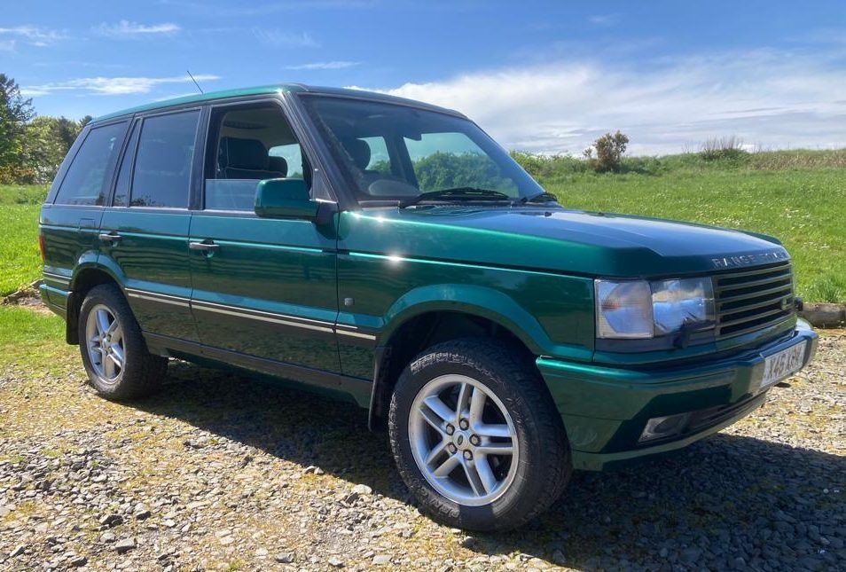 Green Range Rover SUV parked outdoors on a sunny day.