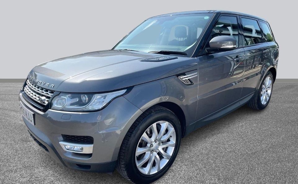 A maroon Range Rover SUV parked on a street, featuring a black roof and silver wheels.