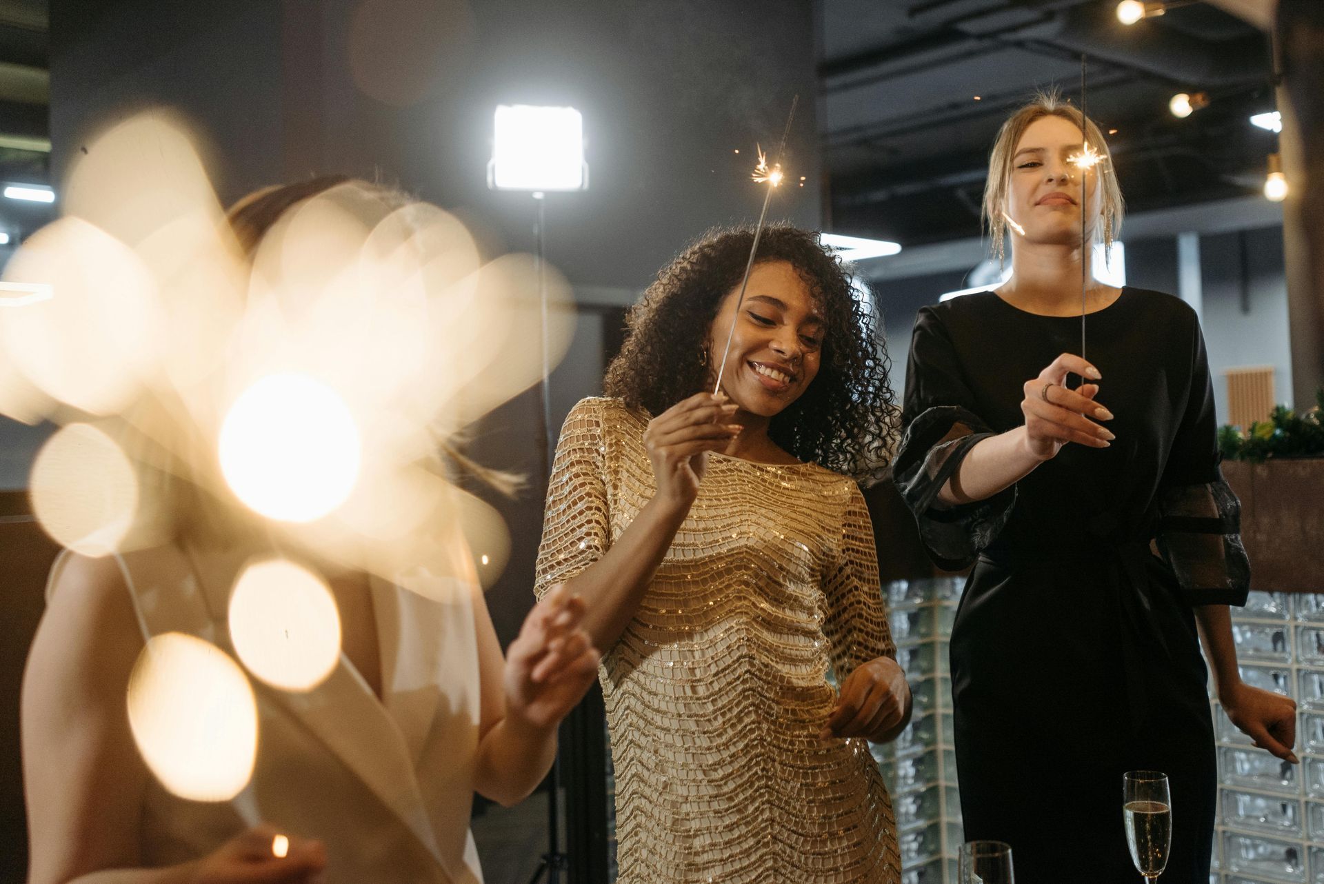 A group of women are holding sparklers and drinking champagne at a party.