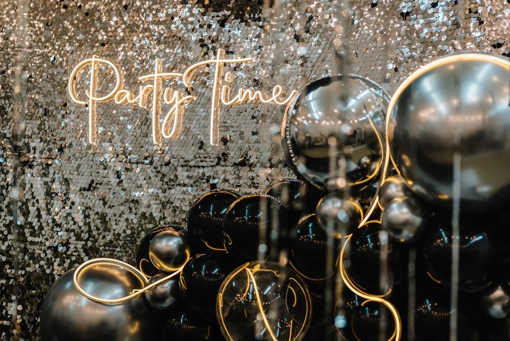A bunch of black and gold balloons are hanging from the ceiling.
