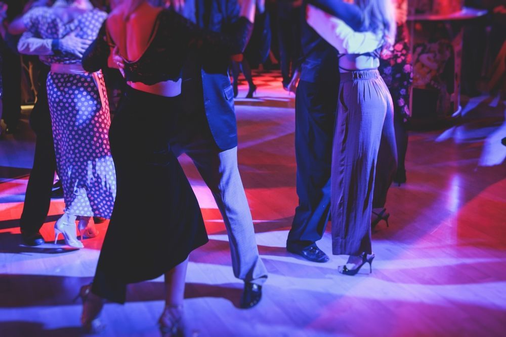 A group of people are dancing tango on a dance floor.