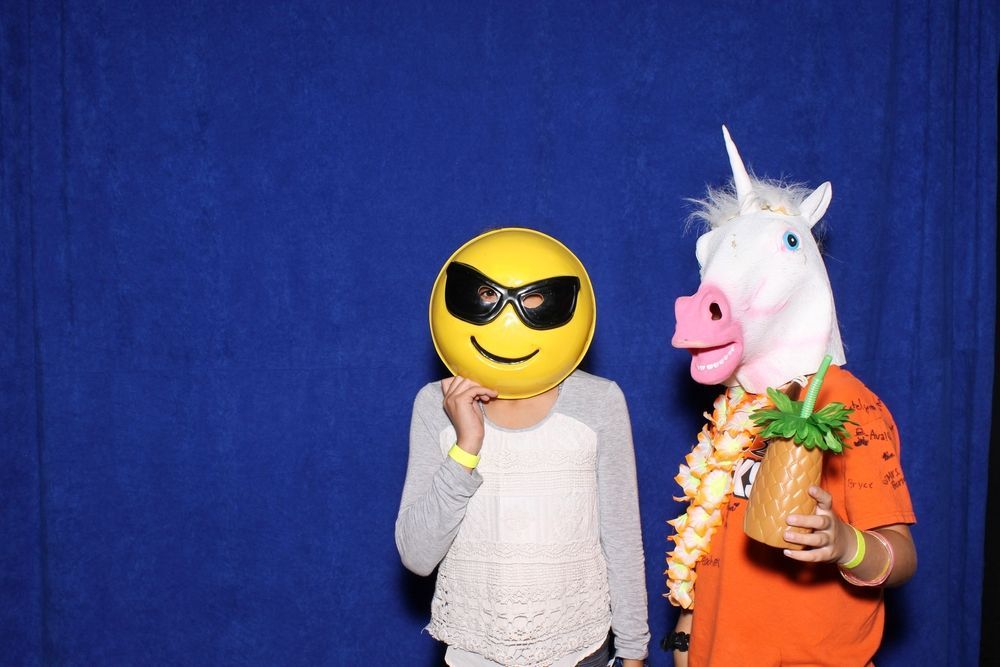 A woman wearing a smiley face mask stands next to a man wearing a unicorn mask.