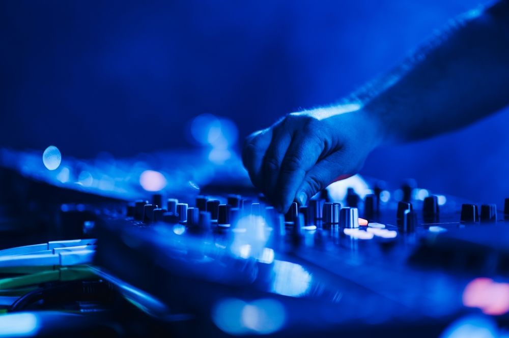 A dj is playing music on a mixer in a dark room.