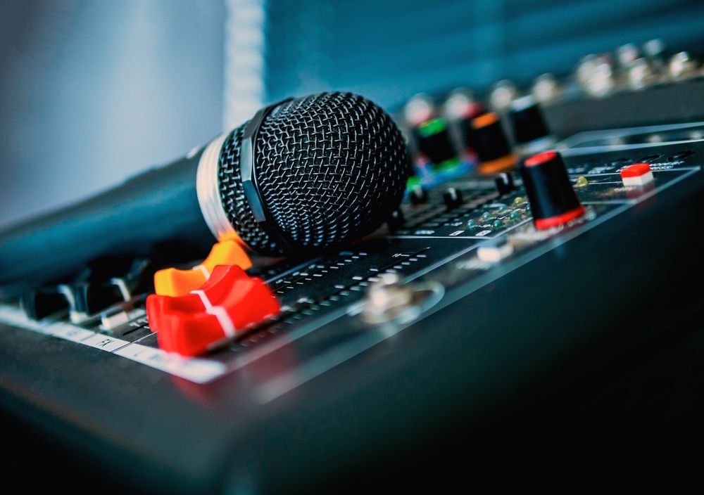 A microphone is sitting on top of a mixer.