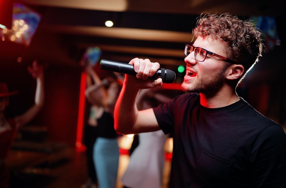 A man is singing into a microphone at a party.