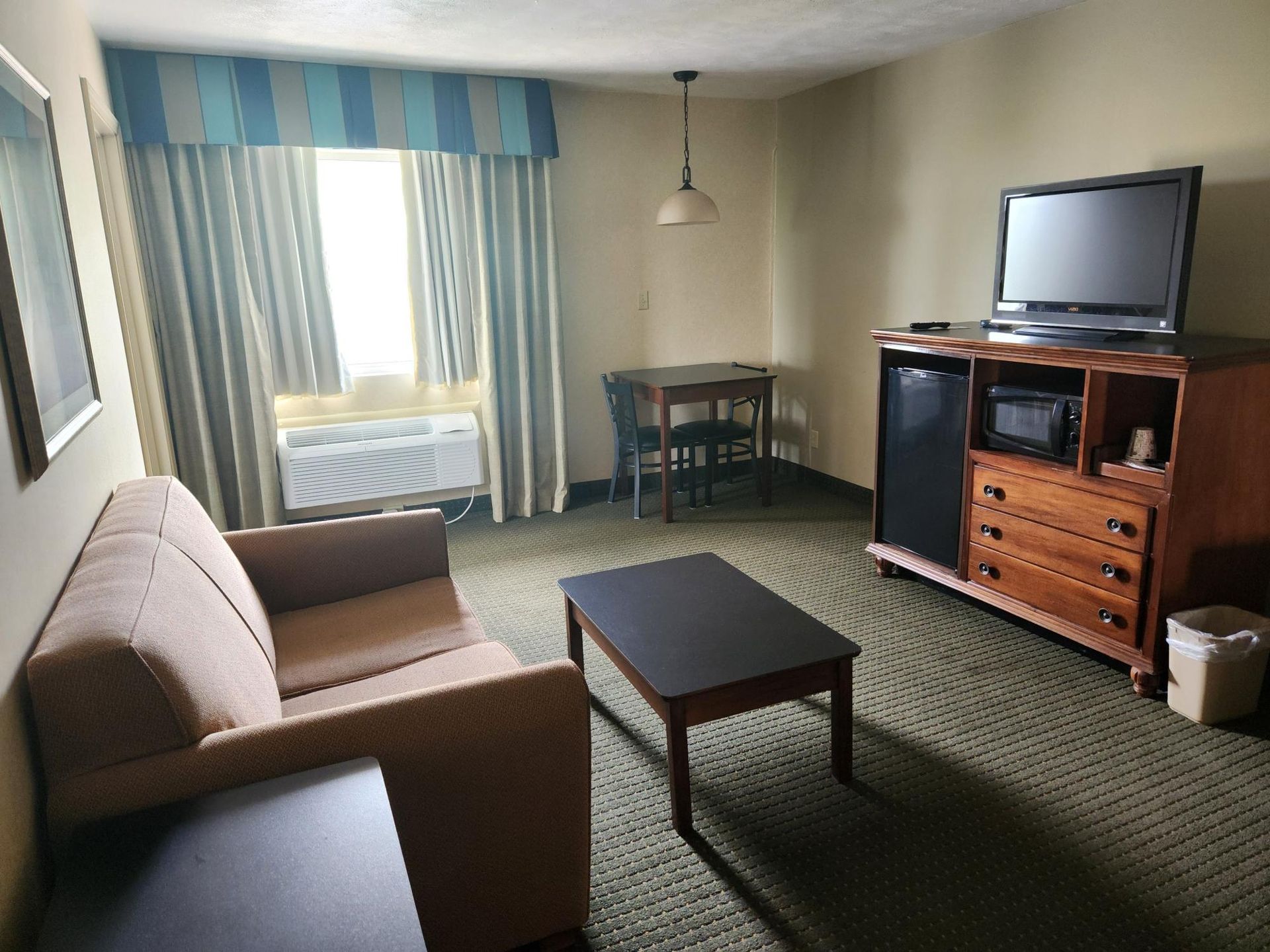 A hotel room with a couch a table and a television
