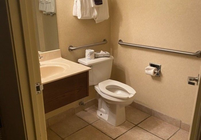 A bathroom with a toilet , sink and mirror.