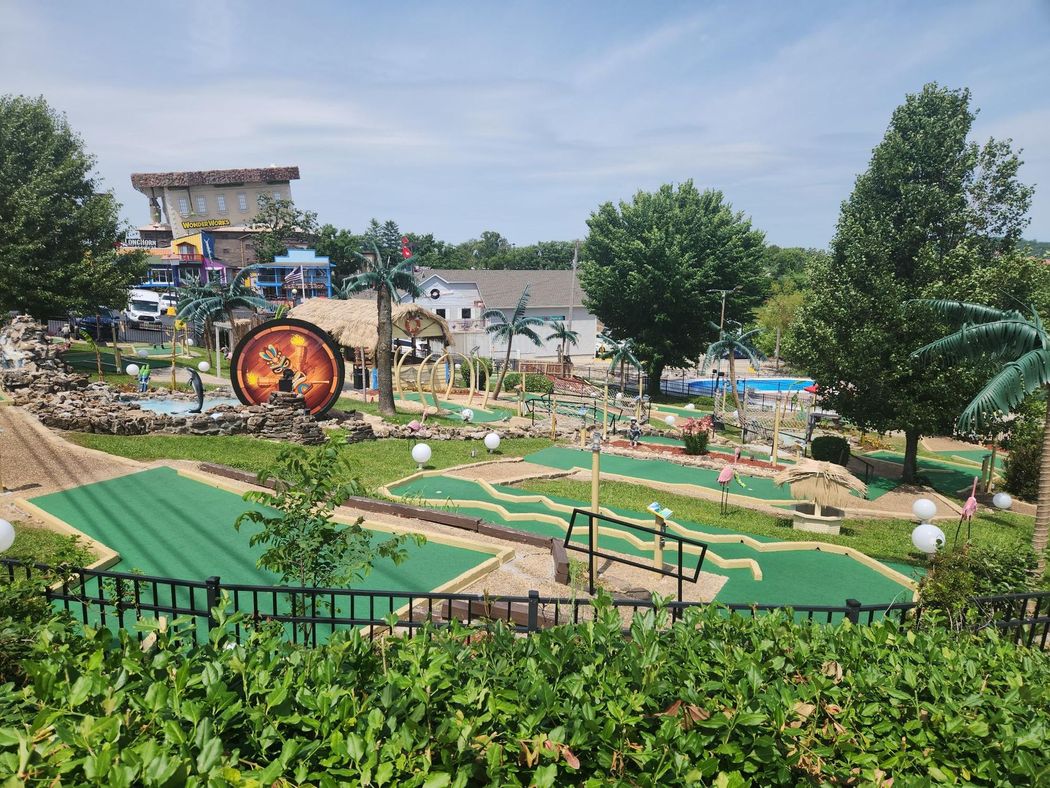 A mini golf course in a park surrounded by trees and bushes.