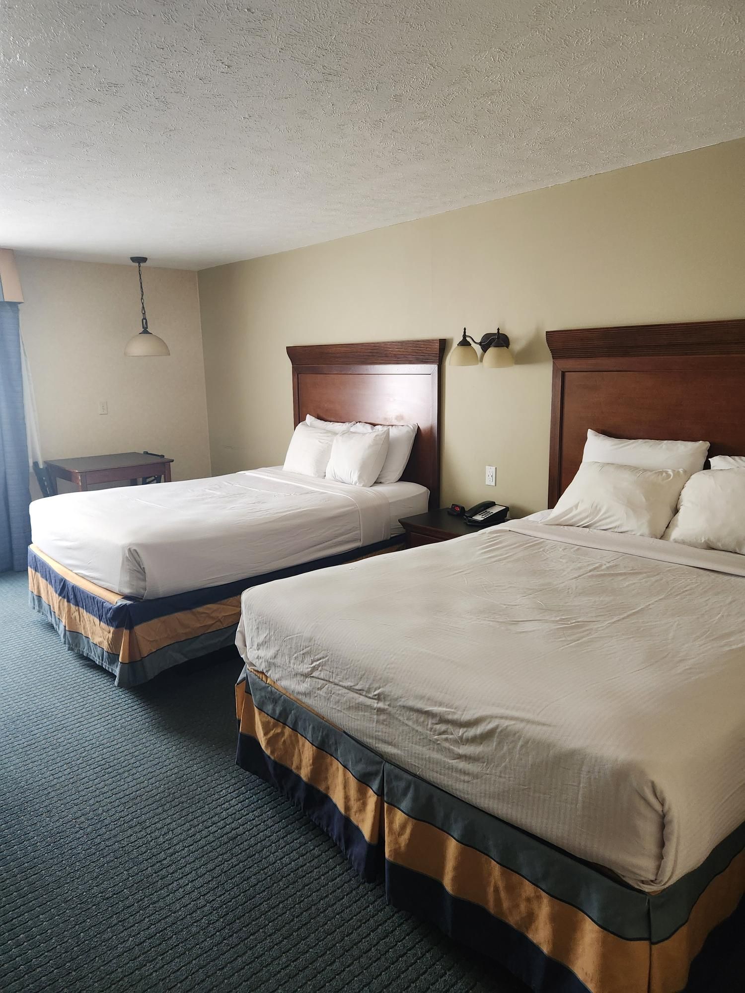 A hotel room with two beds and a nightstand.