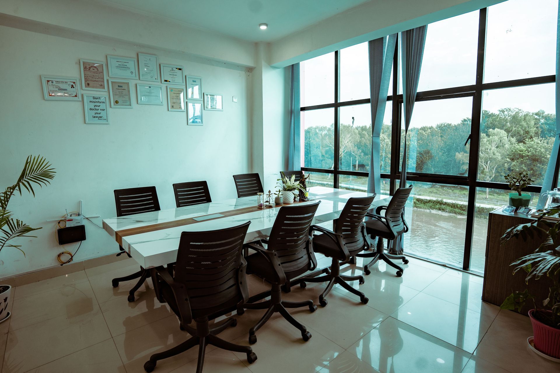 Modern glass-walled conference room with white table, black chairs, and city view