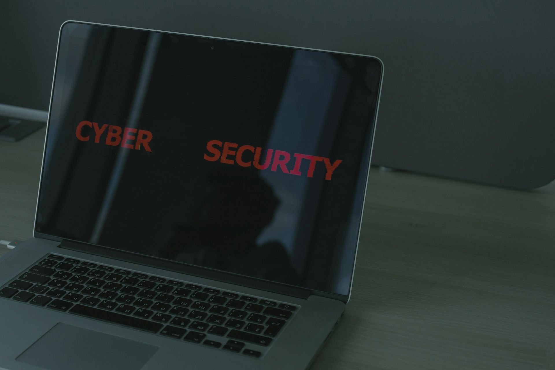 Laptop screen displaying red “CYBER SECURITY” text on a dark background