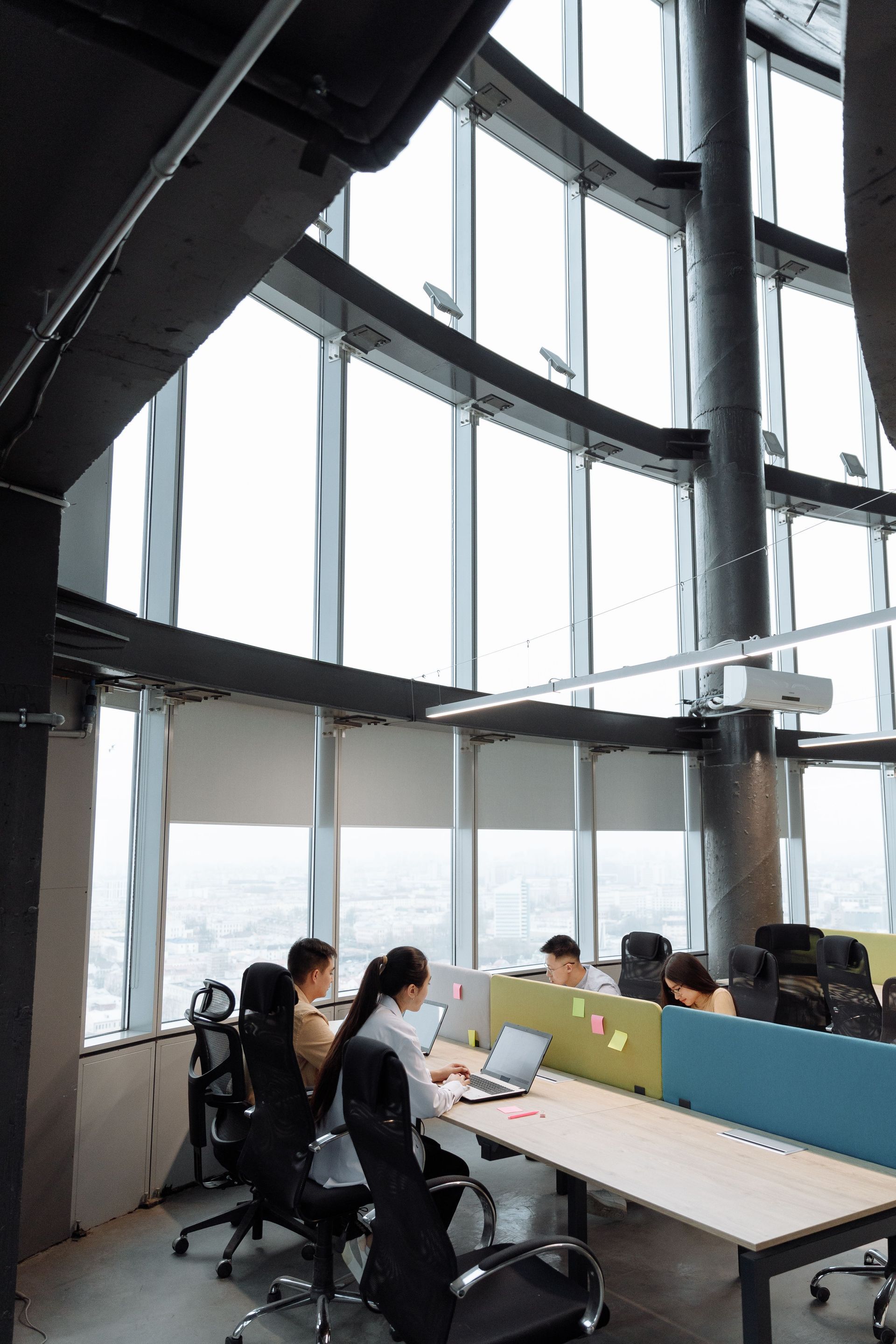 People working at desks in a modern glass-walled office with city views