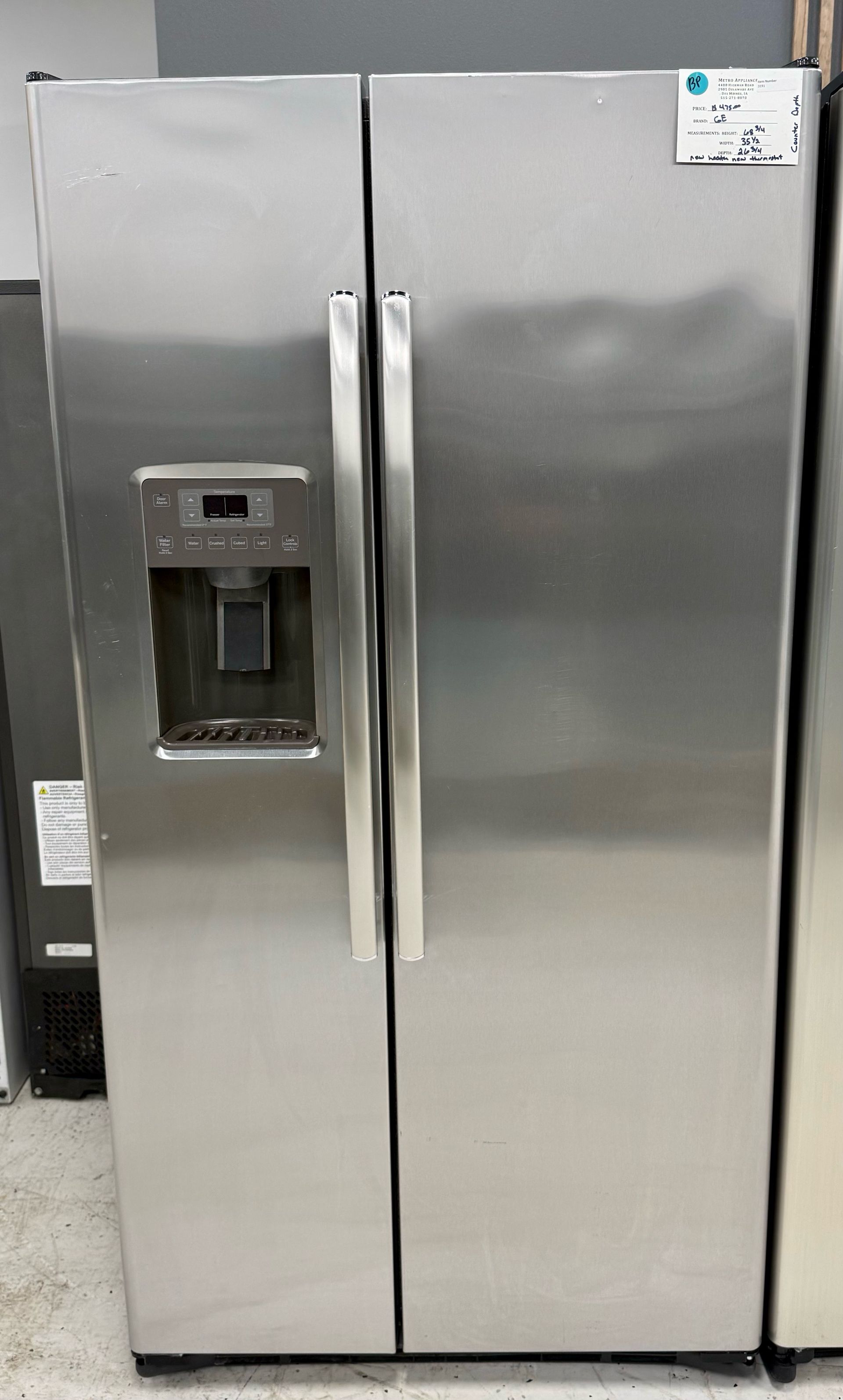 Stainless steel side-by-side refrigerator with water and ice dispenser in a kitchen.
