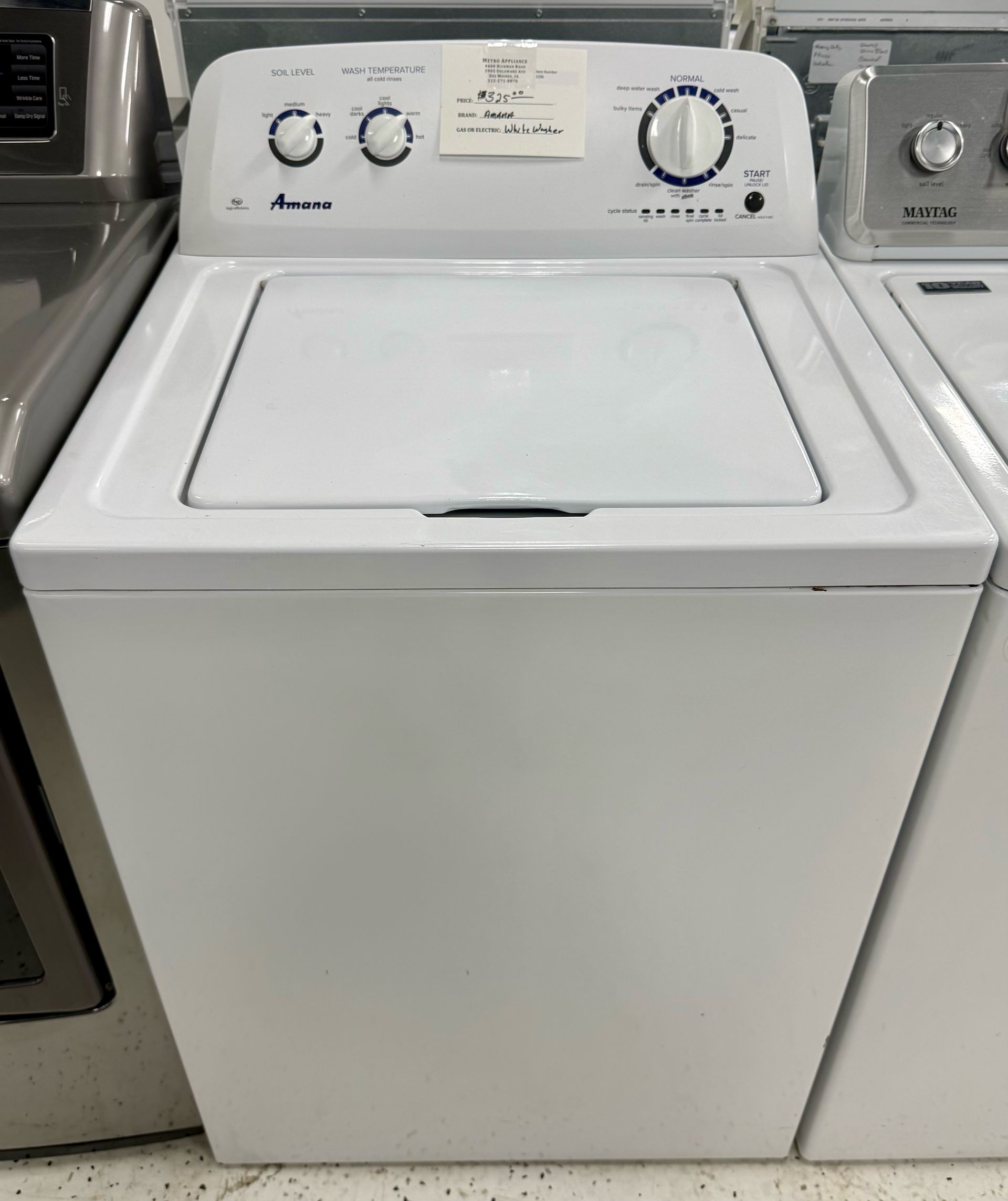White top-loading washing machine with control dials in a laundry aisle