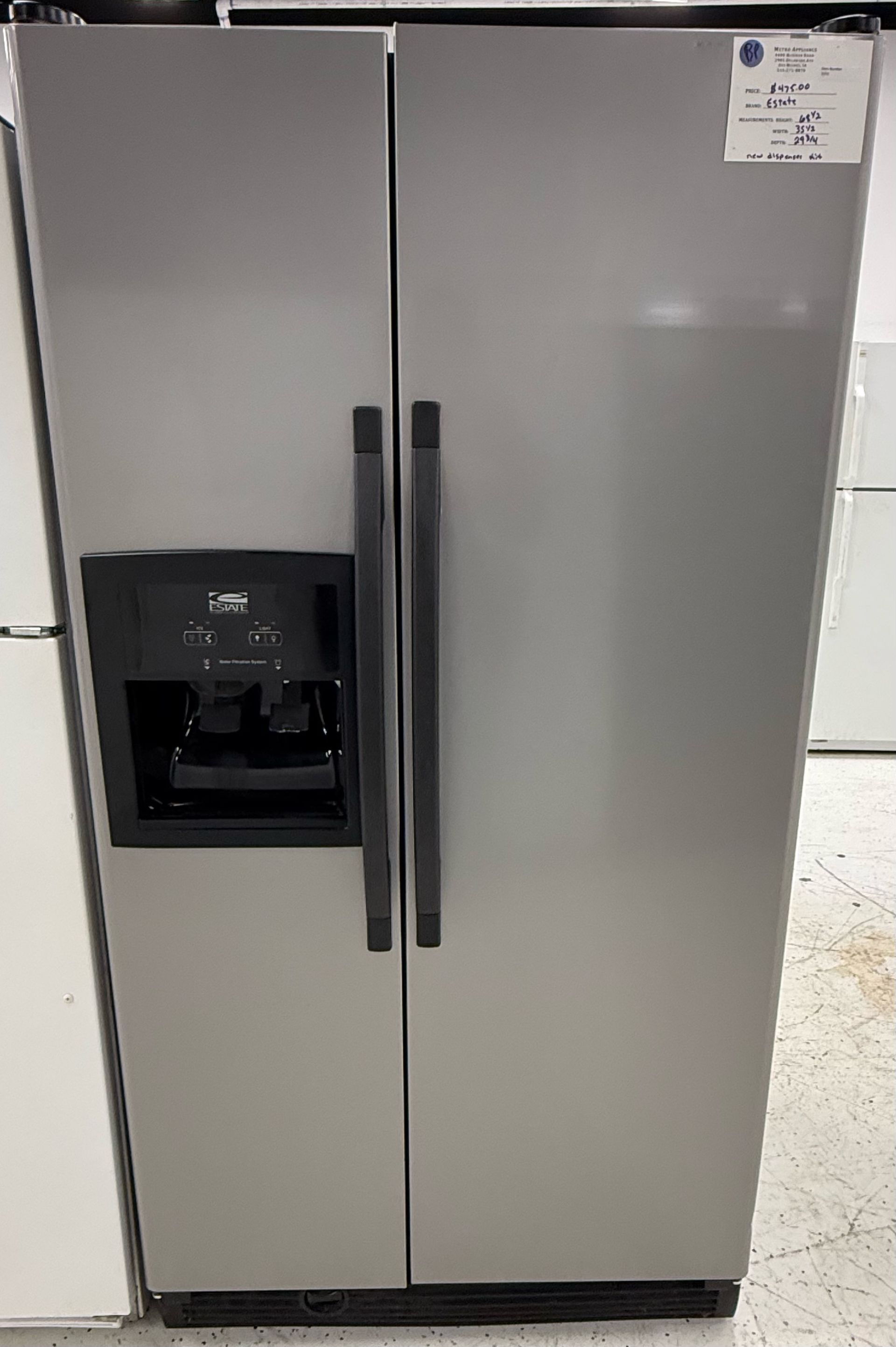 Stainless steel side-by-side refrigerator with water dispenser in a showroom.