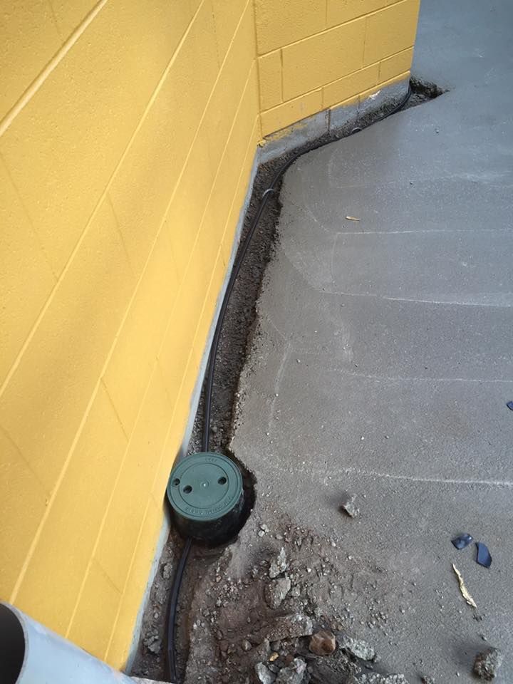 A Green Drain Cover is Sitting on the Ground Next to a Yellow Brick Wall — Territory Pest Control In Katherine, NT
